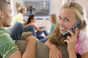 Teenagers Hanging Out In Front Of Television Using Mobile Phones 