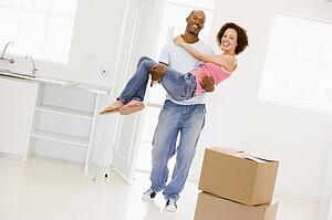Husband holding wife in new home smiling