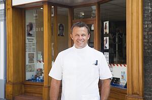 Barber standing outside shop.
