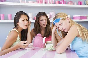 Young woman with a hangover sitting at a table with two friends