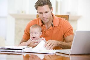 Father and baby in dining room with laptop