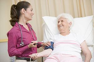 Doctor checking woman's blood pressure in exam room smiling