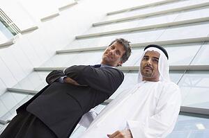 Two businessman standing outdoors by building smiling (high key/selective focus)