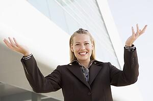 Businesswoman standing outdoors by building smiling with hands out