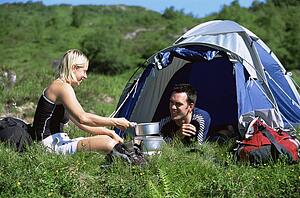Couple outdoors at campsite with pots smiling (selective focus)