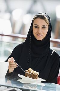 Woman at restaurant eating dessert and smiling (selective focus)