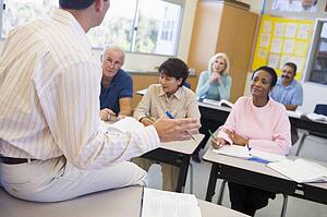Teacher in class lecturing adult students (selective focus)
