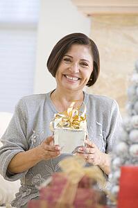 Woman Sitting On Sofa Holding A Christmas Gift