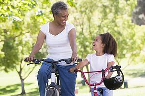 Grandmother and granddaughter on bikes outdoors smiling
