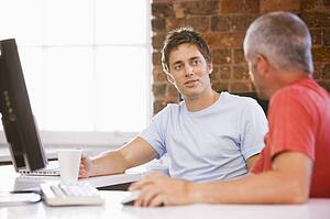 Two businessmen in office drinking coffee and talking