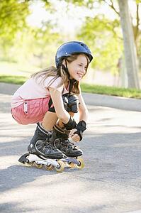 Young girl outdoors on inline skates smiling