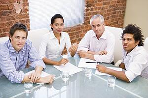 Four businesspeople in boardroom smiling