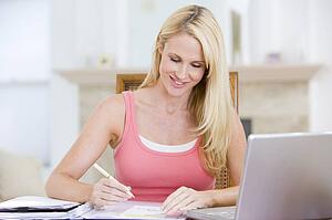 Woman in dining room with laptop smiling