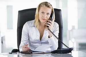 Businesswoman in office with personal organizer open on telephone