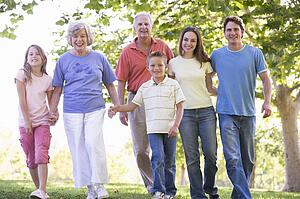 Extended family walking in park holding hands and smiling