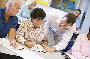 Teacher in class helping adult students (selective focus)
