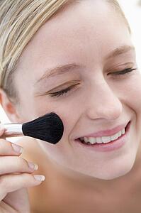 Woman with makeup brush smiling