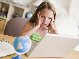 Young Girl Doing Homework On A Laptop
