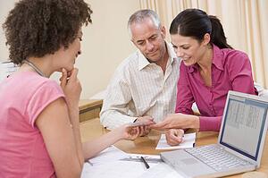 Doctor with laptop and couple in doctor's office smiling