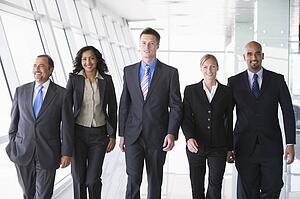 Group of co-workers walking in office space smiling (high key)