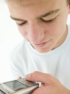 Teenage boy using cellular phone and smiling