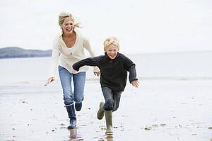 Mother and son running on beach smiling