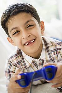 Young boy in living room playing video games and smiling (high key/selective focus)