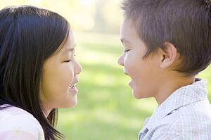 Brother and sister outdoors staring at each other and smiling