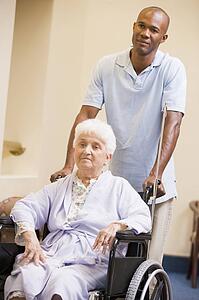Nurse Pushing Senior Woman In Wheelchair