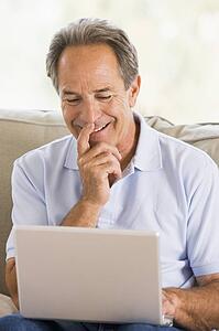 Man in living room with laptop smiling