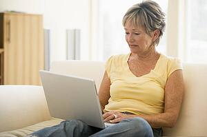 Woman in living room with laptop smiling
