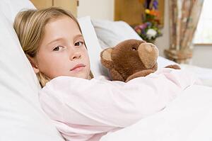 Young Girl Lying In Hospital Bed With Teddy Bear