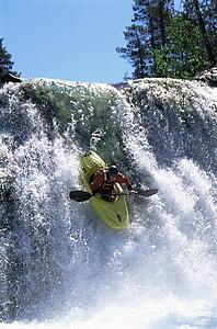 Kayaker in rapids going over waterfall