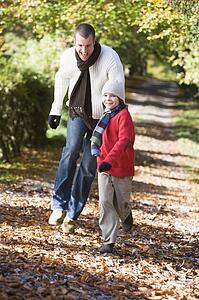 Man and young boy walking on path outdoors smiling (selective focus)