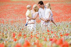 Family standing in poppy field smiling