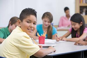 Students in class taking notes with teacher in background (selective focus)