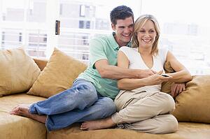 Couple in living room with remote control smiling