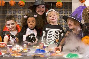 Four young friends and a woman at Halloween eating treats and smiling