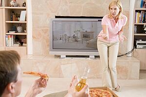 Wife Telling Husband Off For Drinking Beer And Eating Pizza