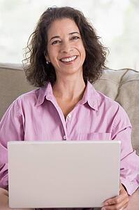 Woman in living room with laptop smiling