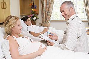 Doctor talking to pregnant woman holding chart and smiling