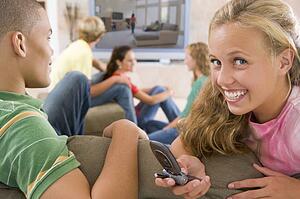 Teenagers Hanging Out In Front Of Television Using Mobile Phones 