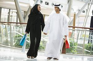 Couple walking in mall holding hands and smiling (selective focus)