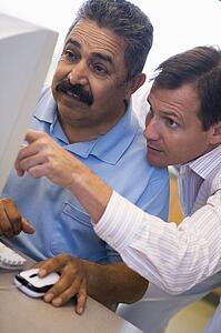 Two men at computer pointing at monitor (high key)