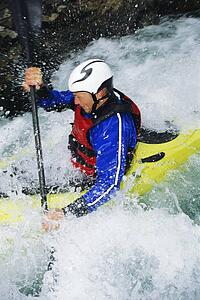 Kayaker in rapids coming over waterfall (selective focus)