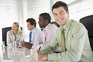 Four businesspeople in a boardroom smiling