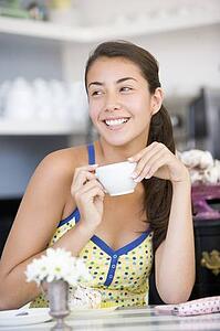 Young woman sitting at a table drinking tea
