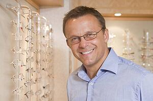 Man trying on eyeglasses at optometrists smiling