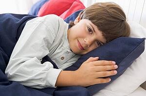 Young Boy Lying Down In His Bed
