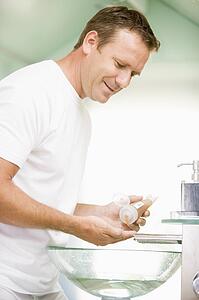 Man in bathroom with hair gel smiling